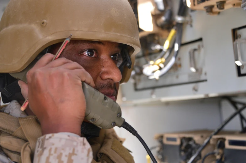 a soldier on the phone, holding a helmet