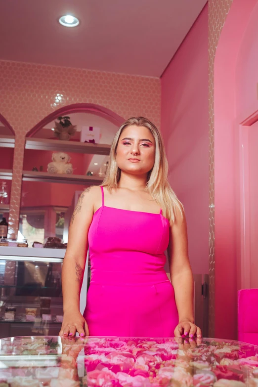 a woman in a pink dress standing in front of an ornate counter