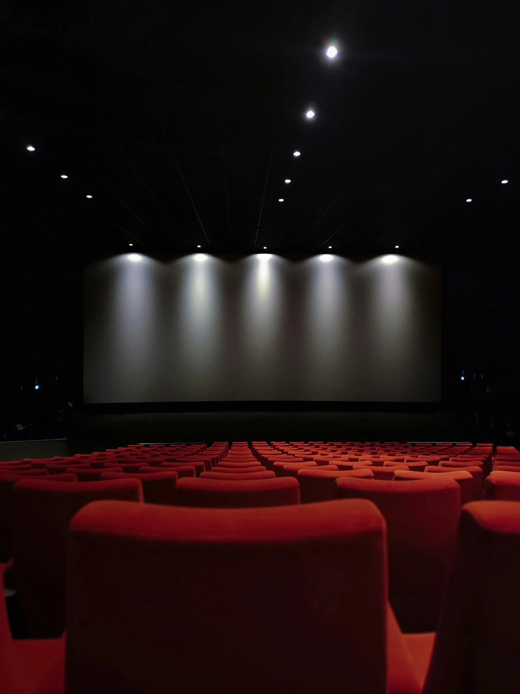 an empty auditorium with red chairs facing away