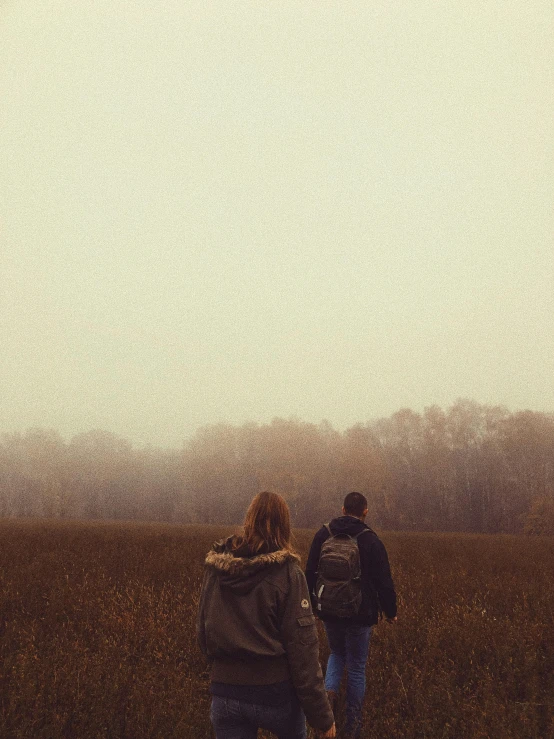 the couple walk through the dry grass holding hands