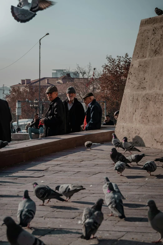 the pigeon is sitting on the pavement as people look on