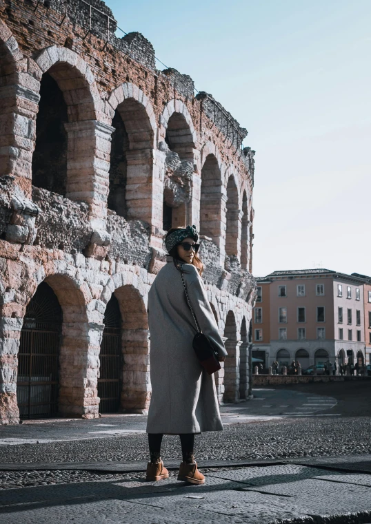 a woman standing on the street next to the wall