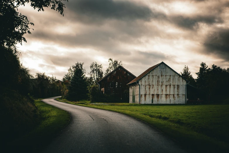 a barn sitting on a rural road near trees