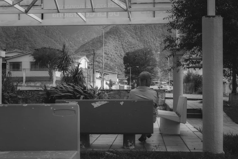 a man is sitting alone on a bench in a city