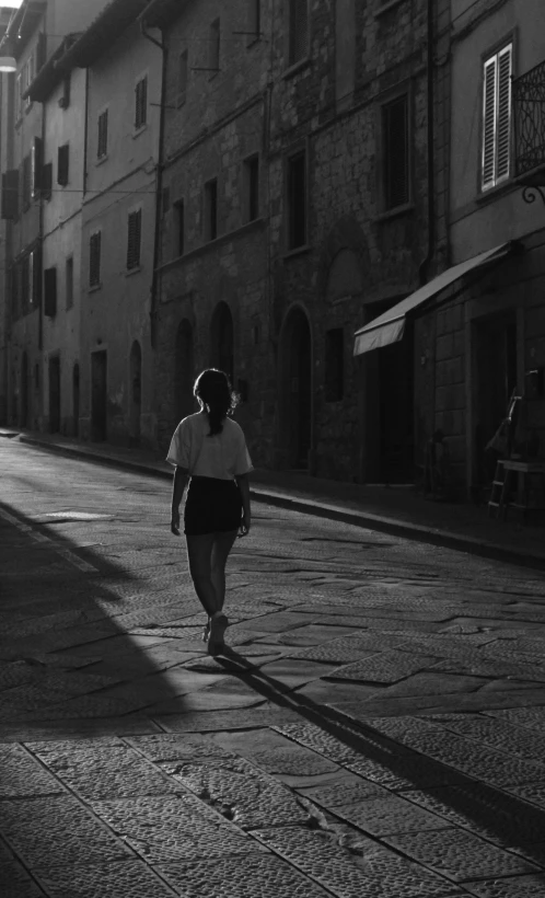 a woman walking down the sidewalk next to an old building