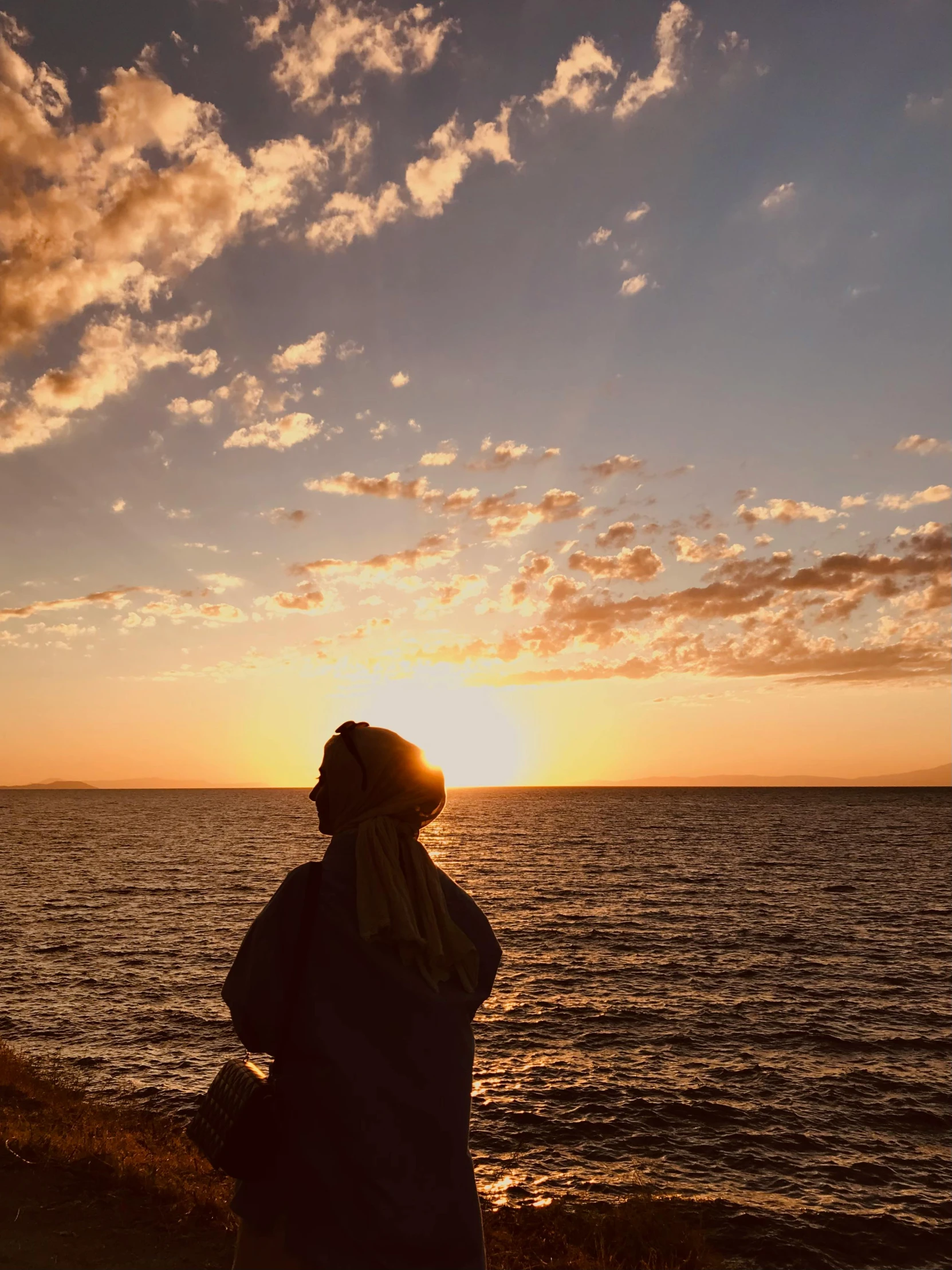 a person standing on the shore watching a beautiful sunset