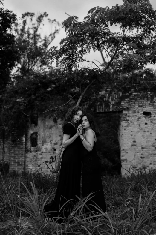 two women posing for the camera in front of an old brick building