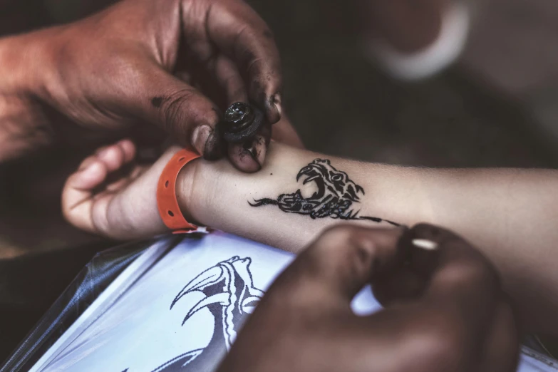 a man getting his tattoo done by a person who is looking on