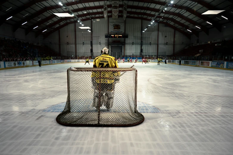 a hockey goalie stands behind the net in an indoor arena