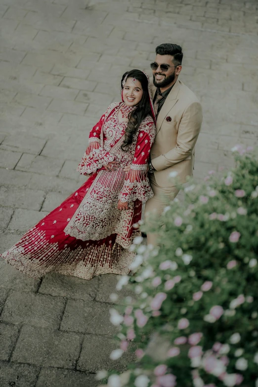 an indian bride and groom posing for a pograph on the side walk