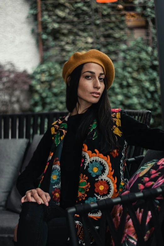 a woman wearing a hat and scarf sits on a couch