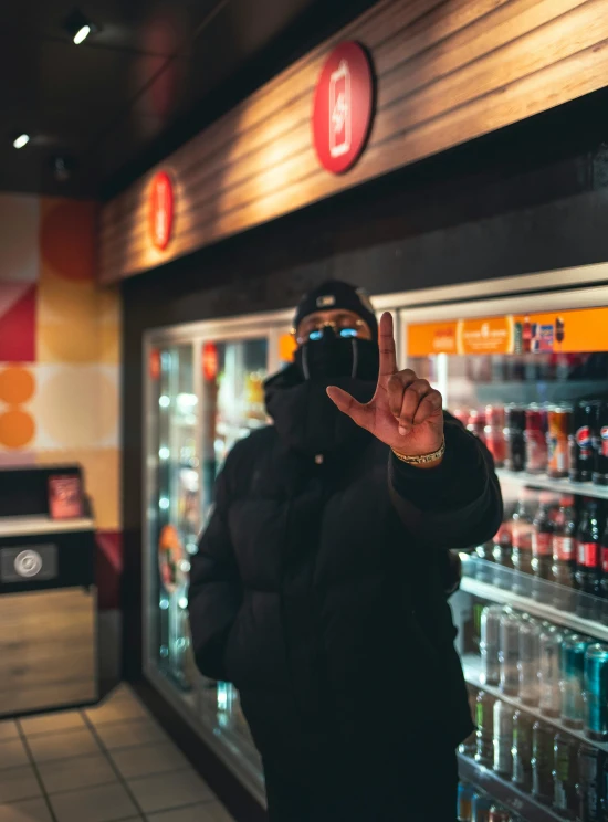 a man in a hooded jacket and cap making a hand gesture