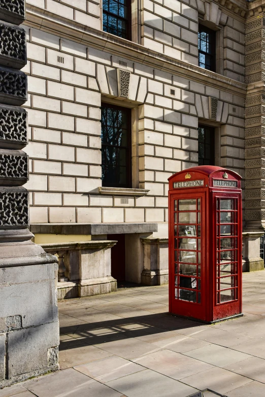 a red phone booth sitting in the middle of a walkway