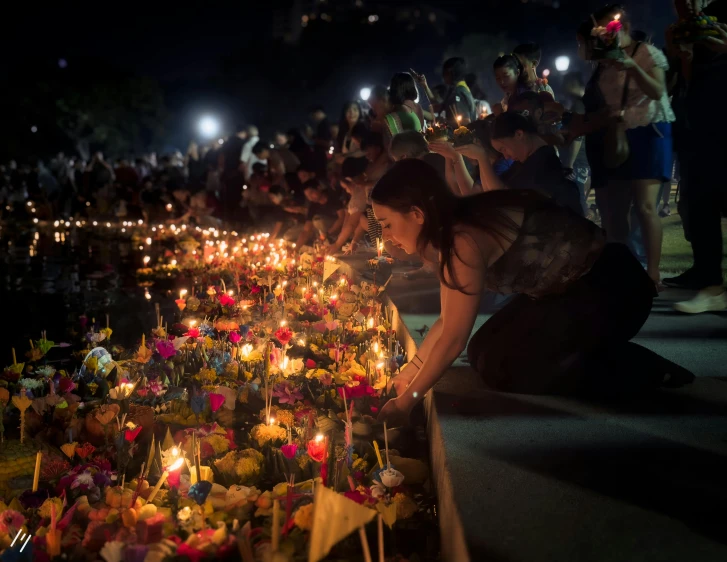 a woman looking at her lighted flowers in a park