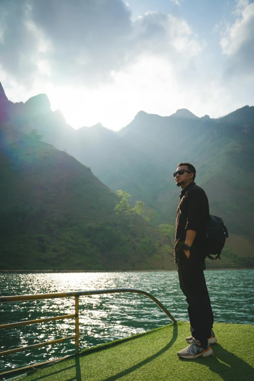 the man is standing on a boat watching the mountains