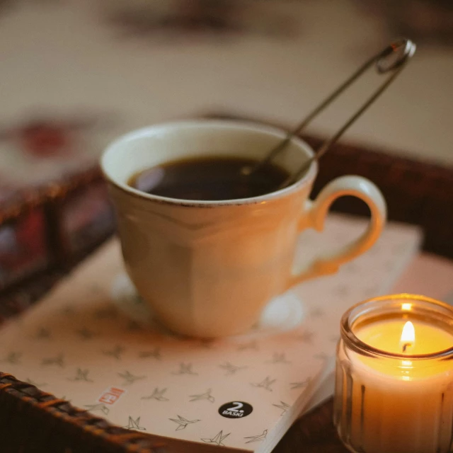 a candle, cup and coaster are sitting on the table