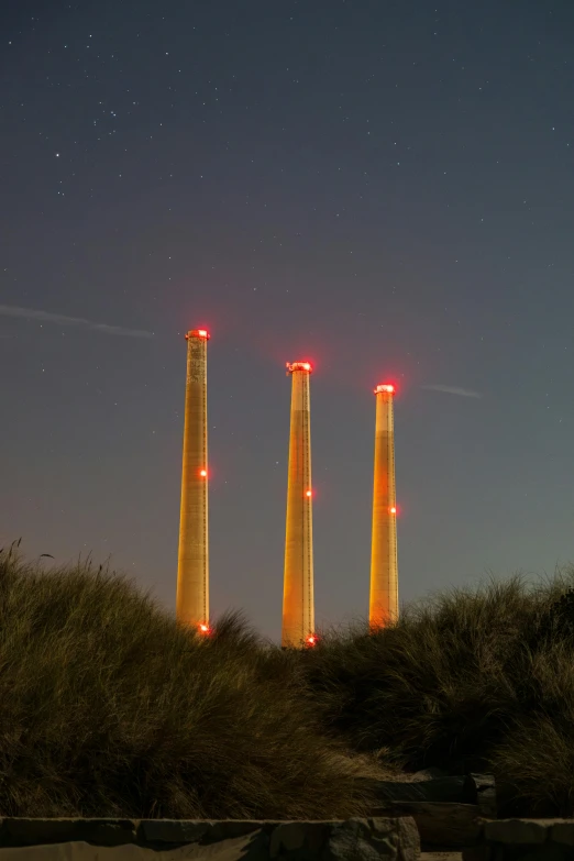 three power towers next to some trees at night