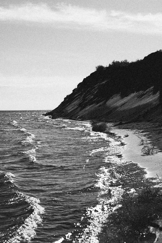 a long line of shoreline leading to the water and a hill on the other side