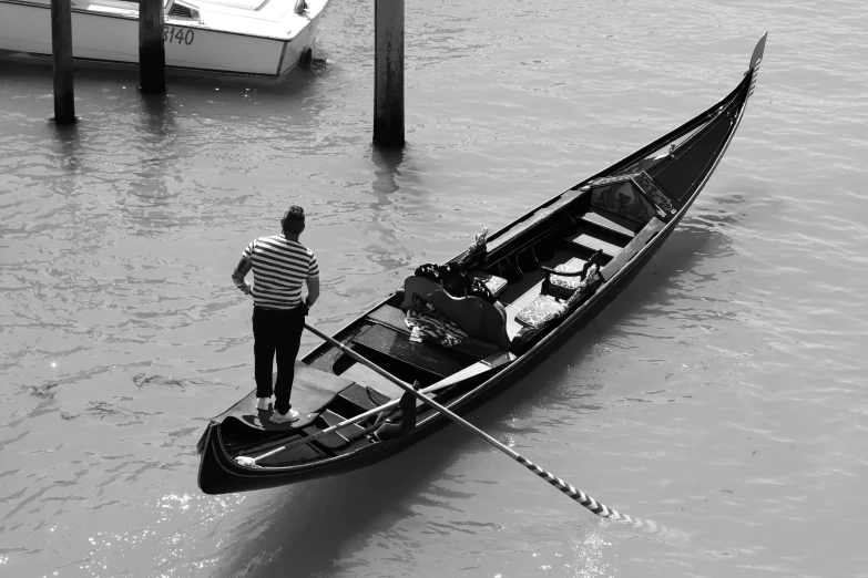 a man stands in the bow of his boat at the edge of water