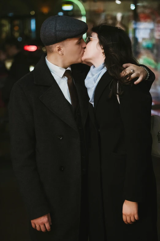 couple kissing on street at night in coat and hat