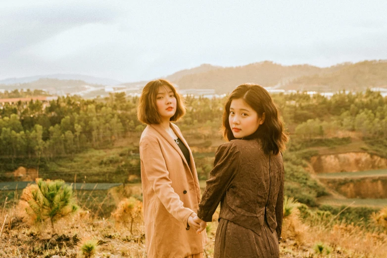 two young ladies holding hands, overlooking a mountain valley