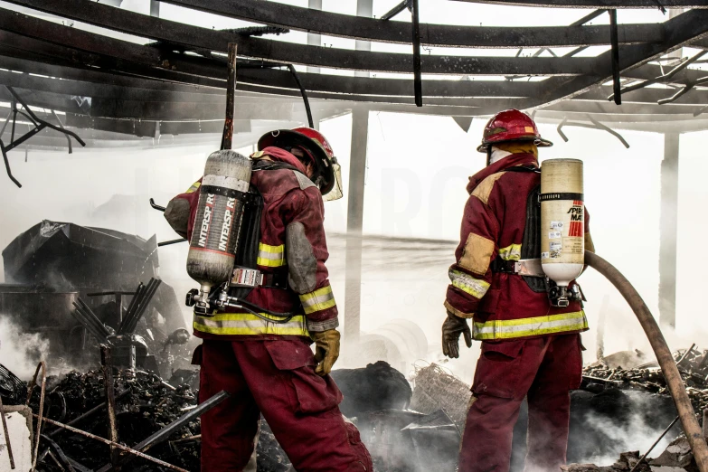 two firefighters walking towards a pile of debris in a warehouse