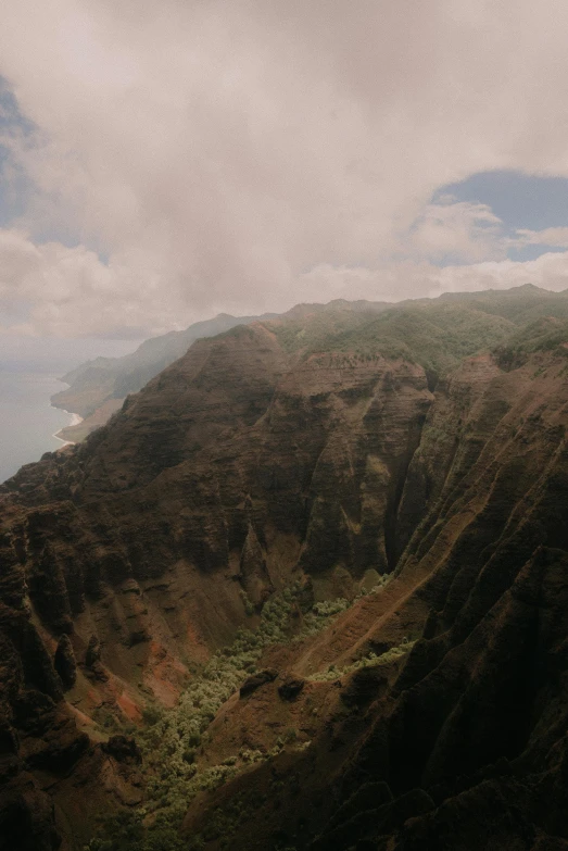 aerial view of the side of mountains and forest under a cloudy sky