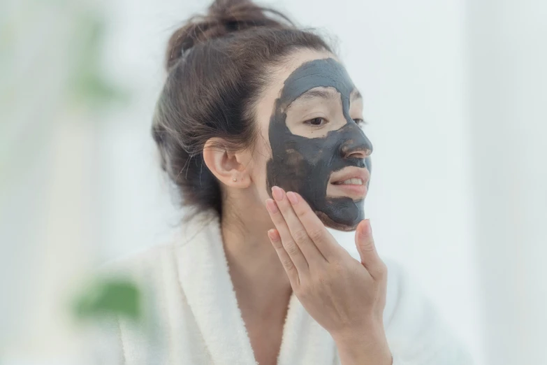 a woman putting a facial mask on her face