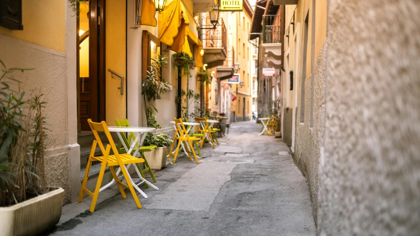 a narrow street with tables and chairs in an urban setting