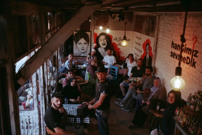 several people seated around tables with bottles and food