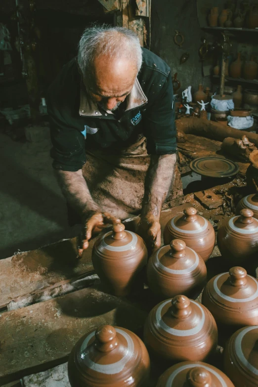 a man with glasses standing over brown pots