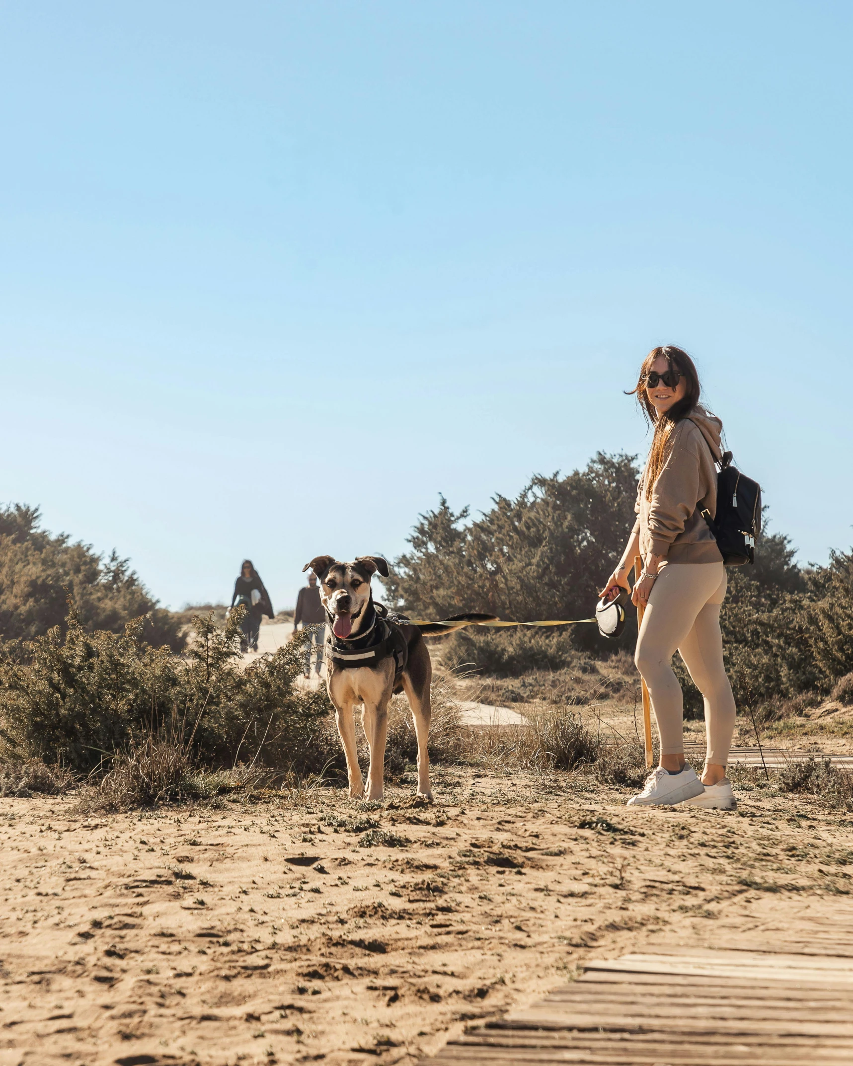 a woman walking on a path while holding a dog in her hand