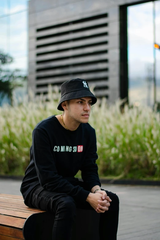 the man is sitting on the bench wearing a hat