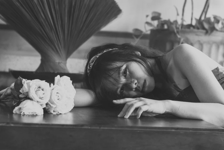 a woman laying down in a table next to some flowers