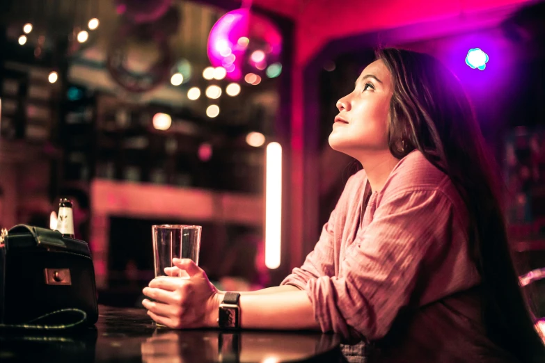 a woman is sitting at a bar with her glass