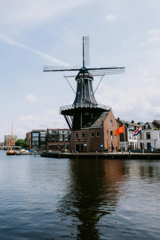 windmill sitting on the water in front of houses