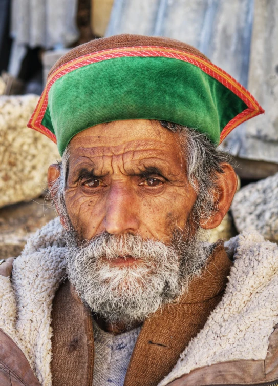 a man with a colorful hat and beard looks into the camera
