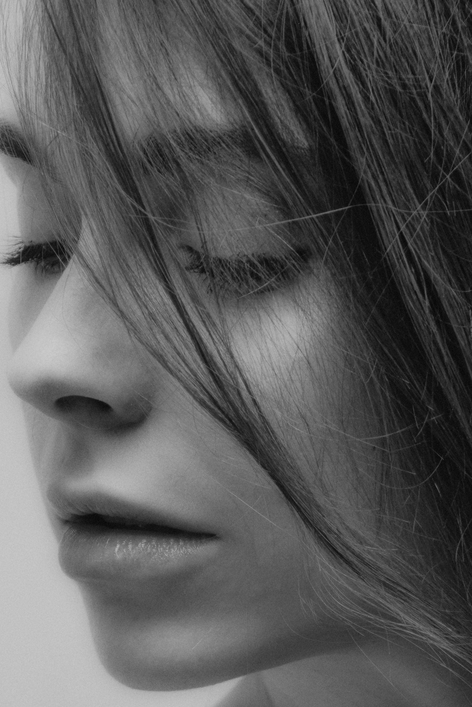 black and white pograph of a woman's face with her long hair blowing in the wind