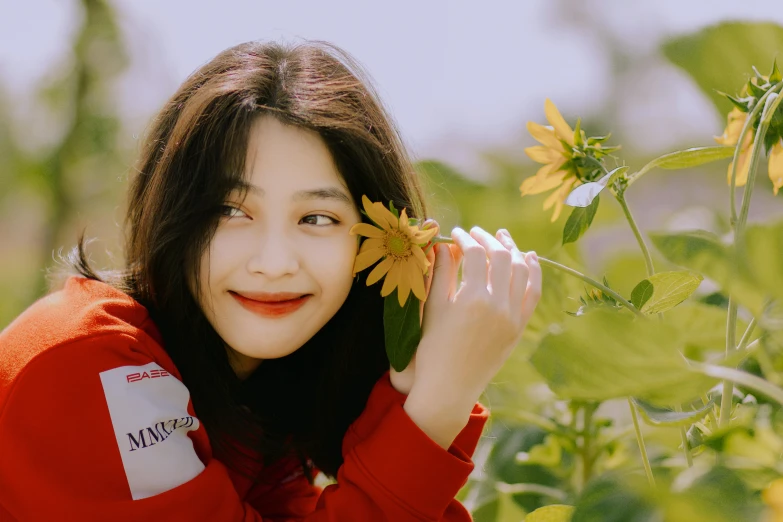 a woman holding a sunflower with both hands