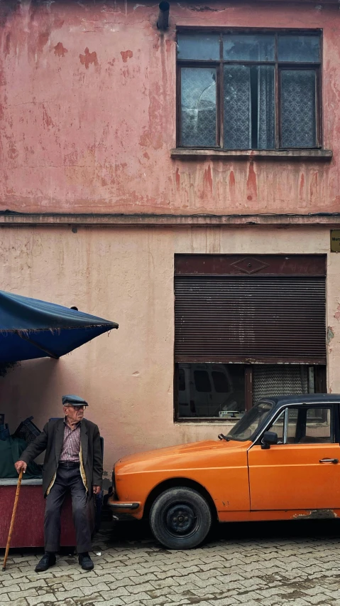 an orange car parked on the street with a man in a hat