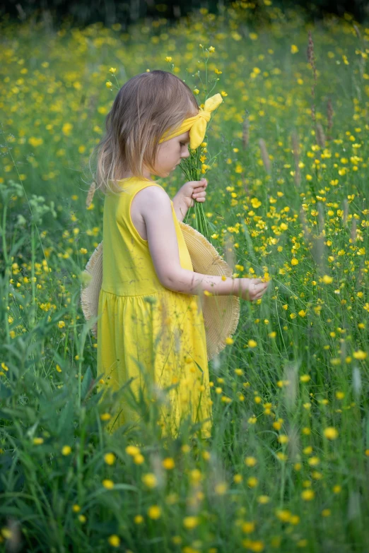 little girl in yellow dress picking flowers from the ground