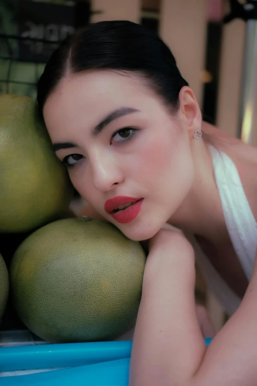 the woman is posing for a picture near a bunch of fruit