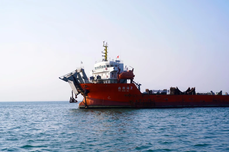 a large red boat sitting on the side of a body of water