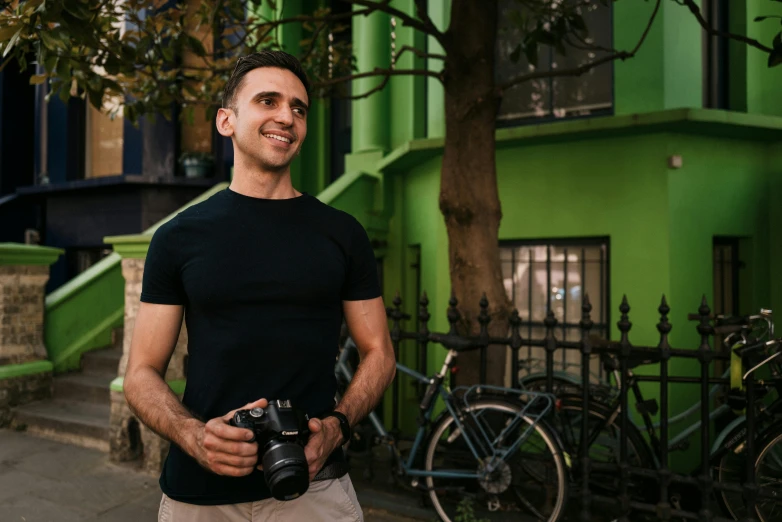 a man stands with a camera outside his apartment