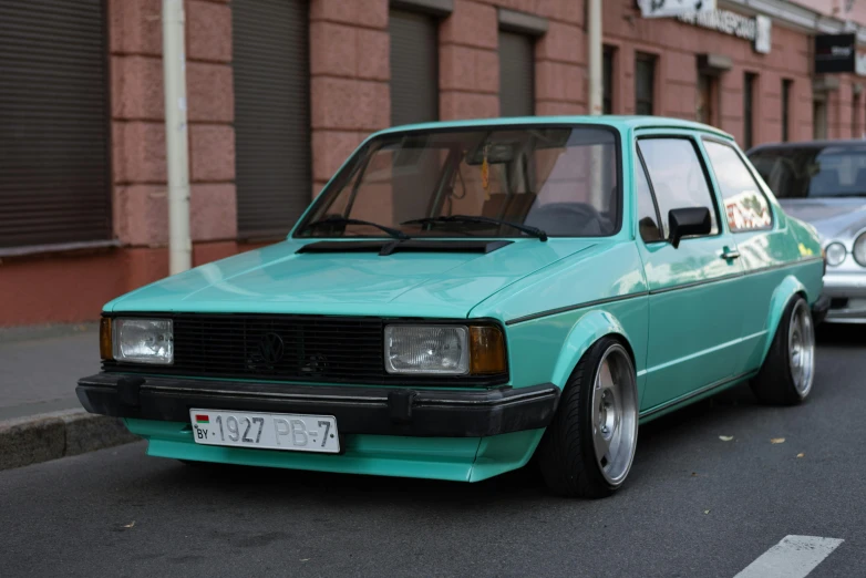 a turquoise van parked near other cars on a city street