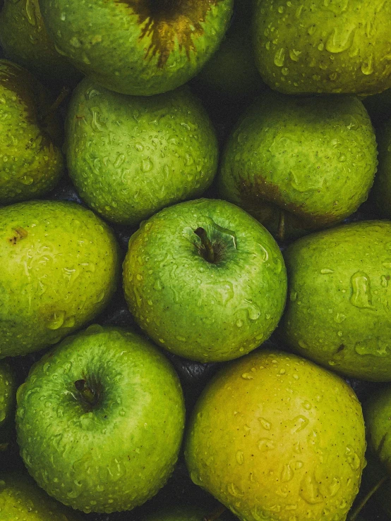 there are many green apples that are stacked on top of each other