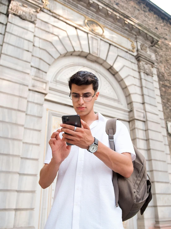 young man looking at cell phone outside a building