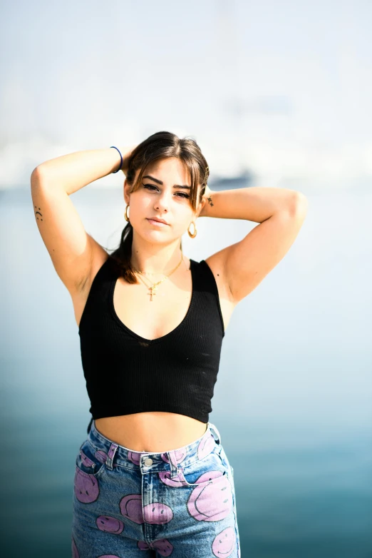 a girl with her hands in her hair is posing by the water