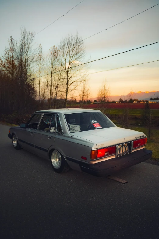 a car sits parked on the side of a road in front of some trees