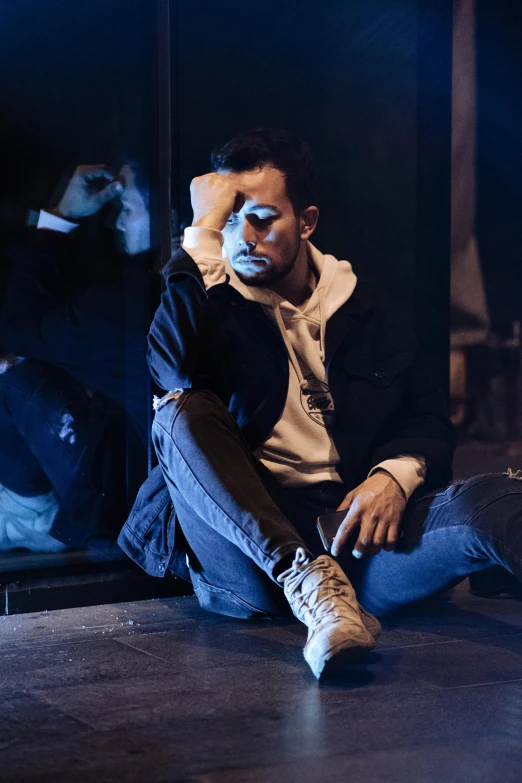 a man sitting on the ground wearing sneakers and smoking a cigarette